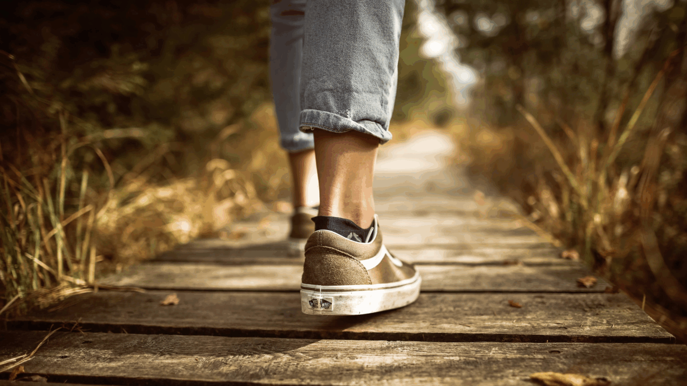 Person walking on a deck through the woods.
