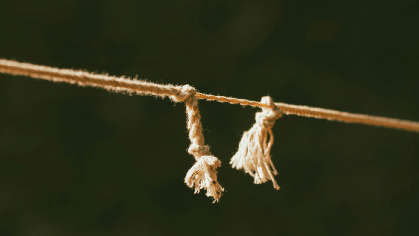 Rope pulled taut which is fraying and holding on by one thread.
